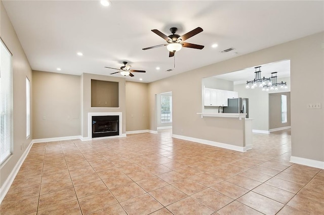 unfurnished living room with light tile patterned floors and ceiling fan with notable chandelier