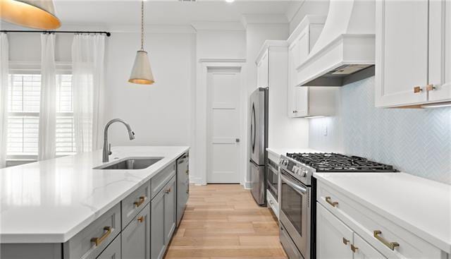 kitchen featuring white cabinets, custom exhaust hood, stainless steel appliances, sink, and hanging light fixtures