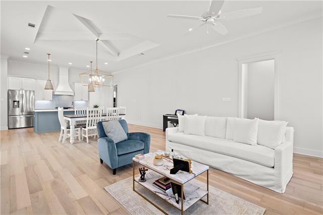 living room with ceiling fan with notable chandelier and light hardwood / wood-style flooring