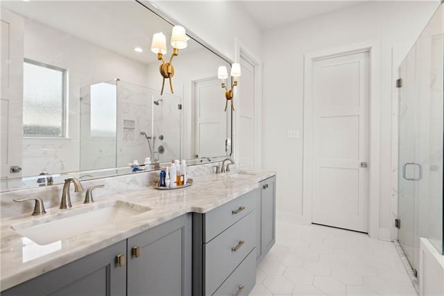 bathroom with a shower with door, vanity, and tile patterned flooring