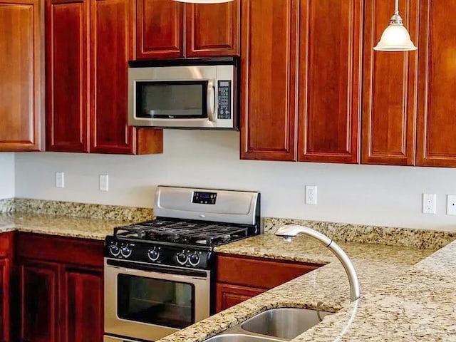 kitchen featuring light stone countertops, stainless steel appliances, and pendant lighting