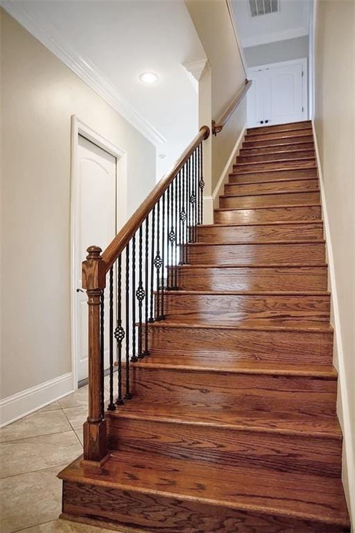 staircase with tile patterned flooring and crown molding