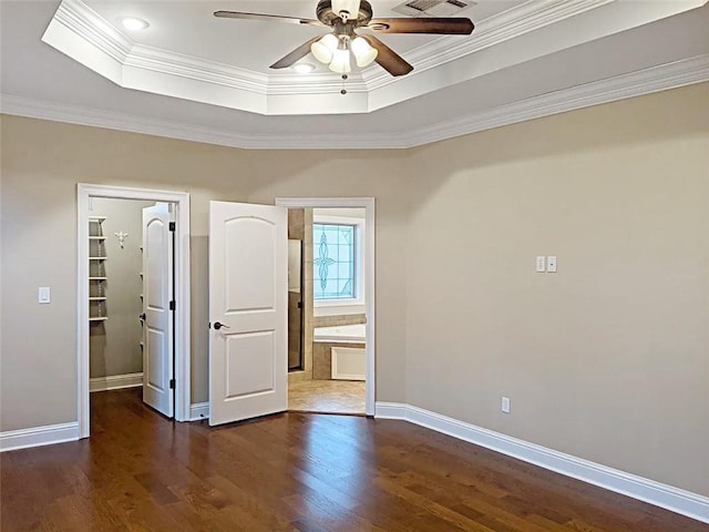 unfurnished room with ceiling fan, dark hardwood / wood-style flooring, crown molding, and a tray ceiling