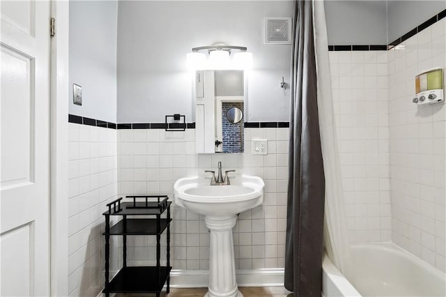 bathroom with shower / tub combo with curtain and tile walls