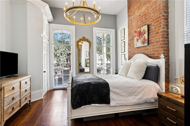 bedroom with a notable chandelier, access to exterior, a brick fireplace, and dark hardwood / wood-style floors