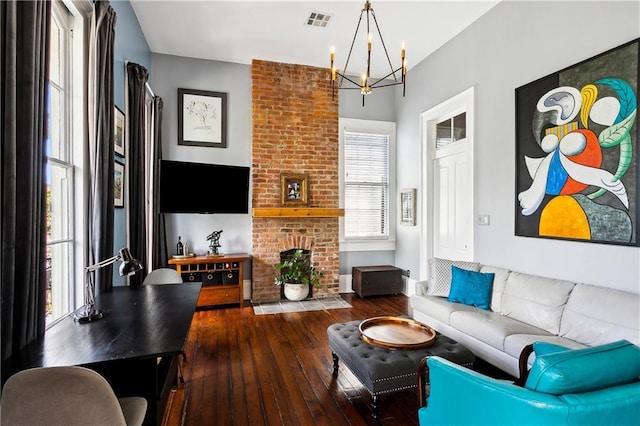 living room featuring a fireplace, dark wood-type flooring, and an inviting chandelier