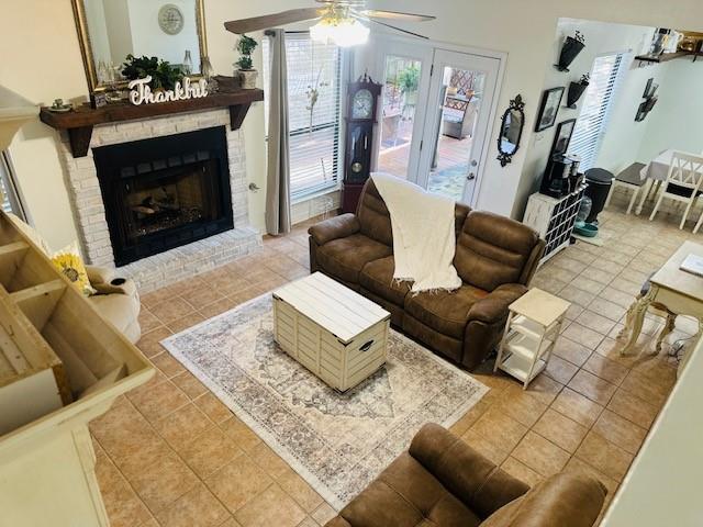 tiled living room with ceiling fan and a brick fireplace