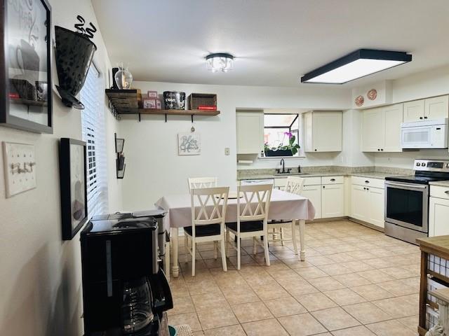 kitchen with light tile patterned floors, stainless steel electric range oven, white cabinets, and sink