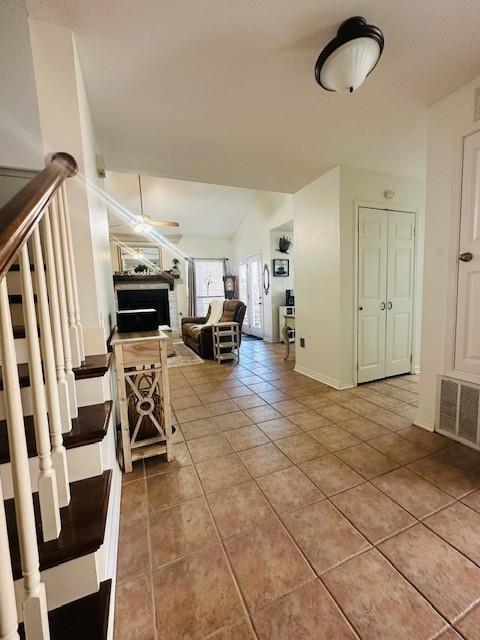 interior space featuring ceiling fan, vaulted ceiling, and tile patterned flooring