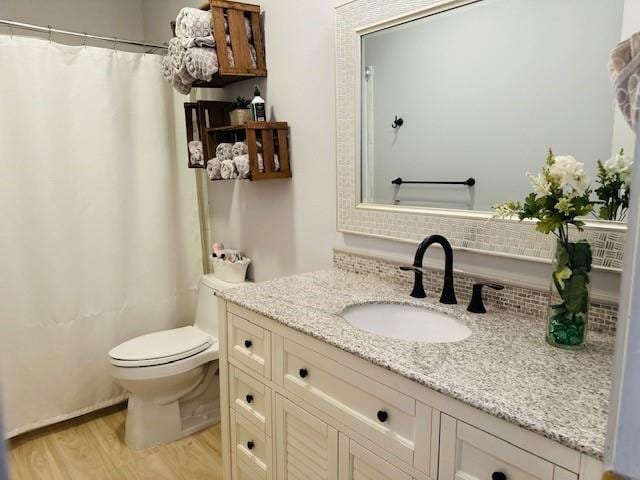 bathroom featuring wood-type flooring, toilet, vanity, and a shower with curtain