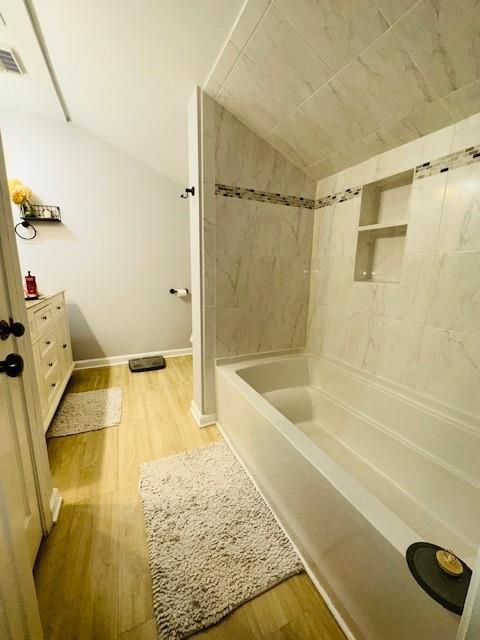 bathroom featuring tiled shower / bath and hardwood / wood-style flooring