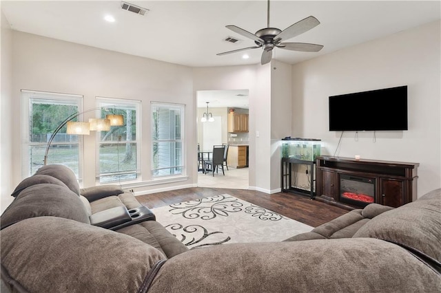 living room with hardwood / wood-style flooring, a wealth of natural light, and ceiling fan with notable chandelier