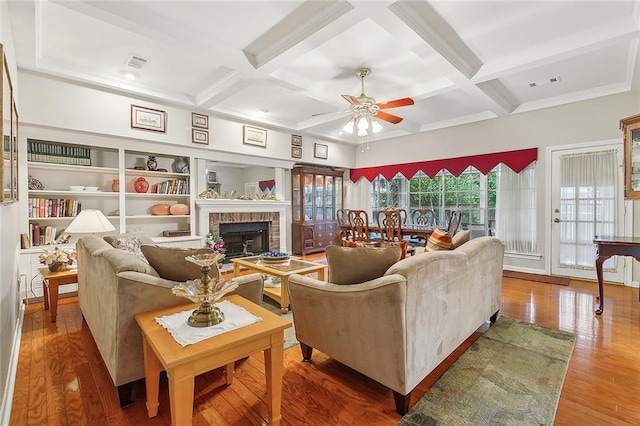 living room with ceiling fan, hardwood / wood-style flooring, a brick fireplace, and coffered ceiling