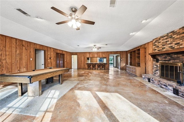 recreation room with ceiling fan, a fireplace, pool table, and wooden walls