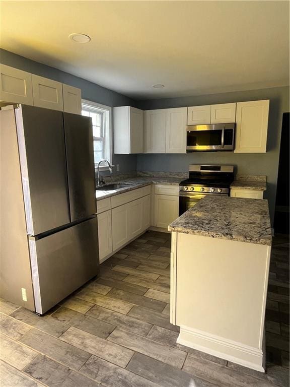 kitchen with light stone countertops, sink, stainless steel appliances, and white cabinetry