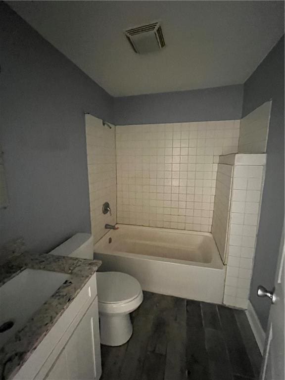 full bathroom with toilet, tiled shower / bath combo, hardwood / wood-style flooring, and vanity