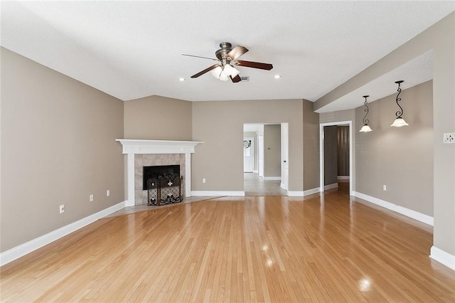 unfurnished living room featuring ceiling fan, a tile fireplace, and light hardwood / wood-style flooring