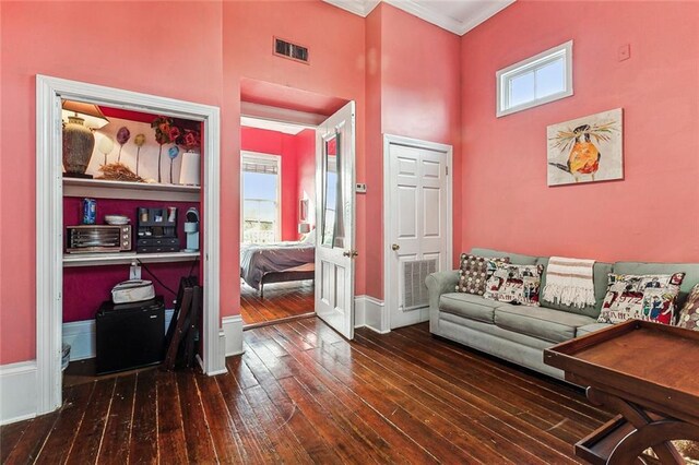 living room with dark wood-type flooring, ornamental molding, and a towering ceiling