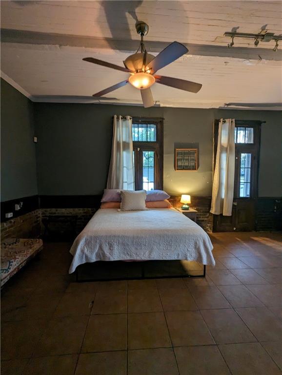 tiled bedroom featuring ceiling fan and crown molding