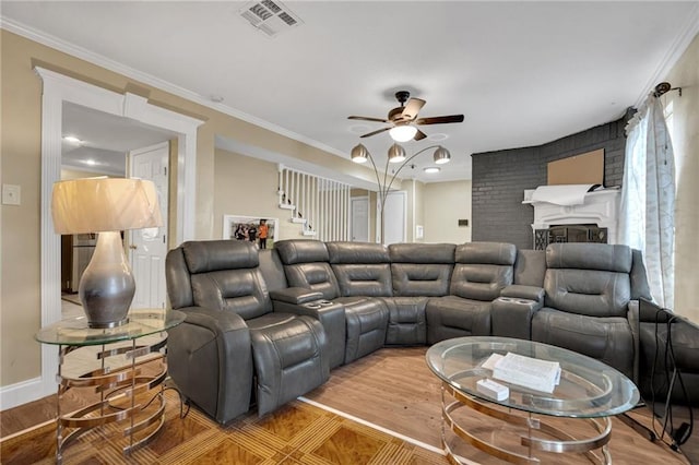 home theater room featuring ceiling fan, ornamental molding, a fireplace, and hardwood / wood-style floors