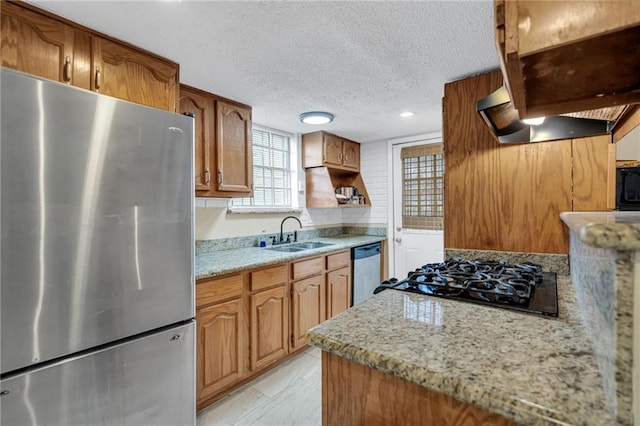 kitchen featuring extractor fan, sink, stainless steel appliances, a textured ceiling, and light stone counters