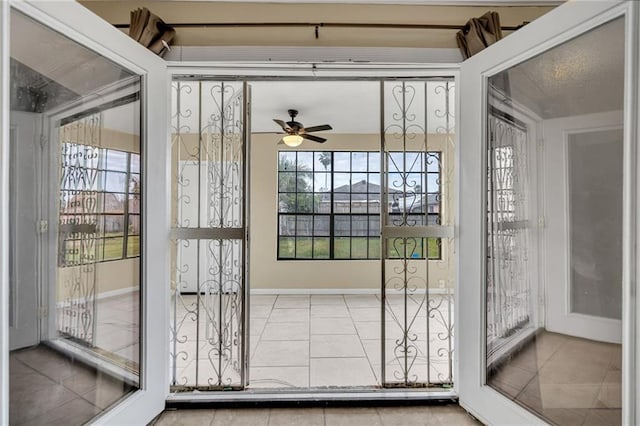 doorway featuring ceiling fan and tile patterned floors