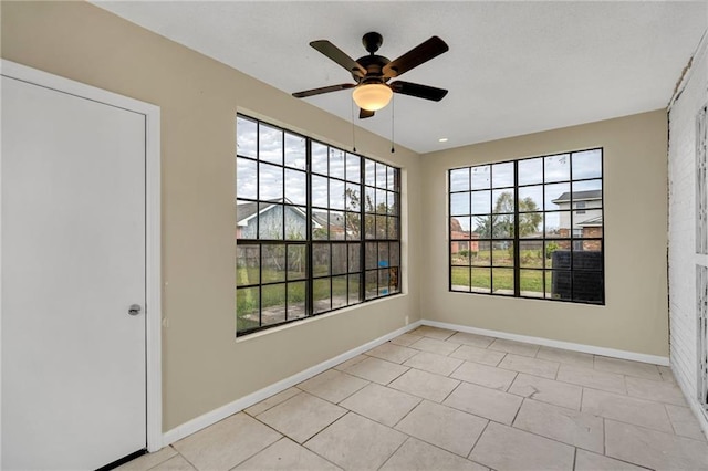 spare room featuring ceiling fan, a healthy amount of sunlight, and light tile patterned floors