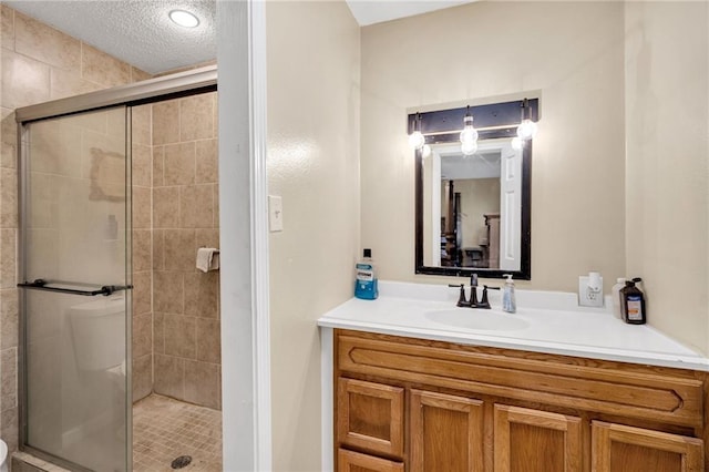 bathroom with a textured ceiling, an enclosed shower, and vanity