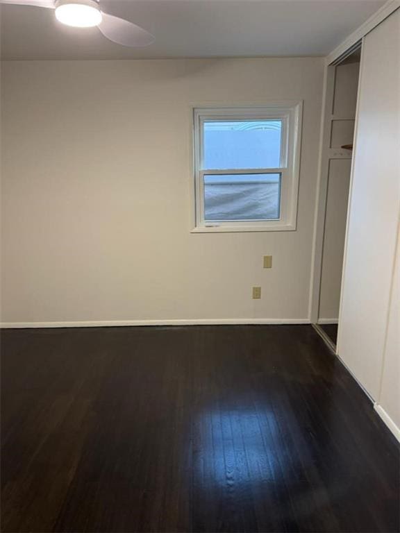 unfurnished bedroom featuring dark hardwood / wood-style flooring, a closet, and ceiling fan