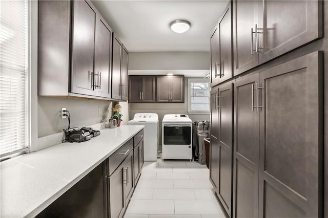 laundry area with light tile patterned floors, washing machine and dryer, a wealth of natural light, and cabinets