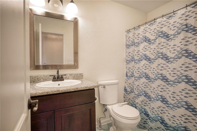 bathroom with toilet, vanity, and walk in shower