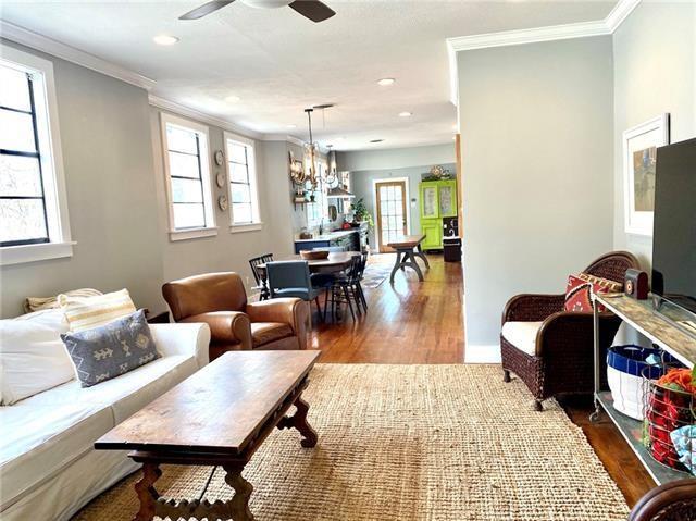 living room with crown molding, hardwood / wood-style flooring, and ceiling fan with notable chandelier