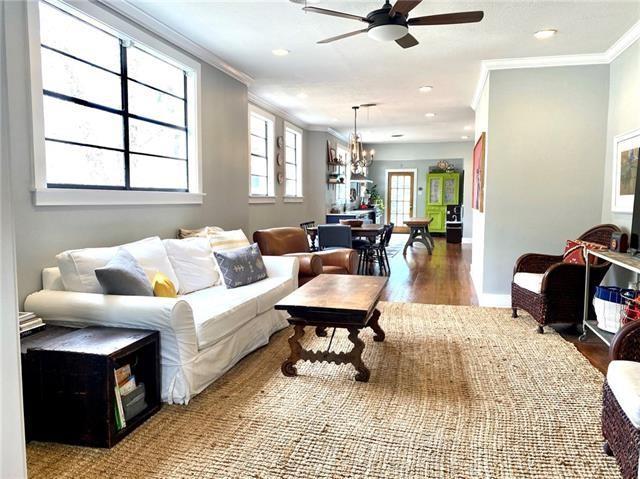 living room with hardwood / wood-style floors, crown molding, ceiling fan with notable chandelier, and a healthy amount of sunlight