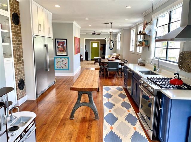 kitchen featuring wall chimney range hood, sink, blue cabinetry, ceiling fan, and appliances with stainless steel finishes