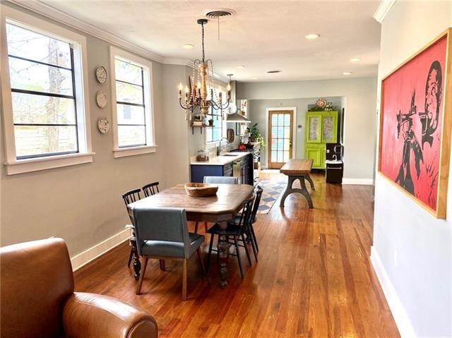 dining area featuring a notable chandelier, crown molding, hardwood / wood-style floors, and sink