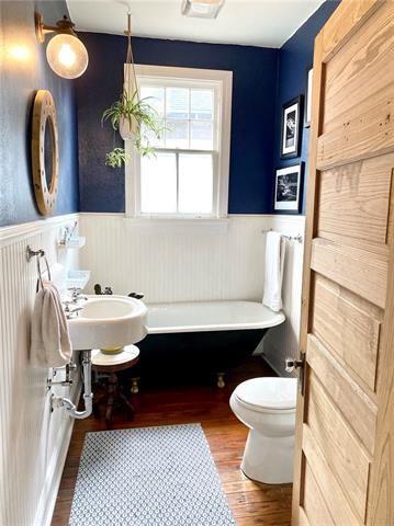 bathroom featuring a washtub, wood-type flooring, and toilet