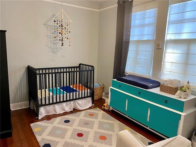 bedroom featuring a nursery area and dark wood-type flooring