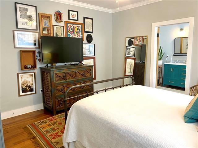 bedroom featuring ornamental molding, ensuite bathroom, and dark hardwood / wood-style flooring