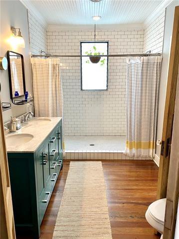 bathroom featuring vanity, hardwood / wood-style floors, curtained shower, and ornamental molding