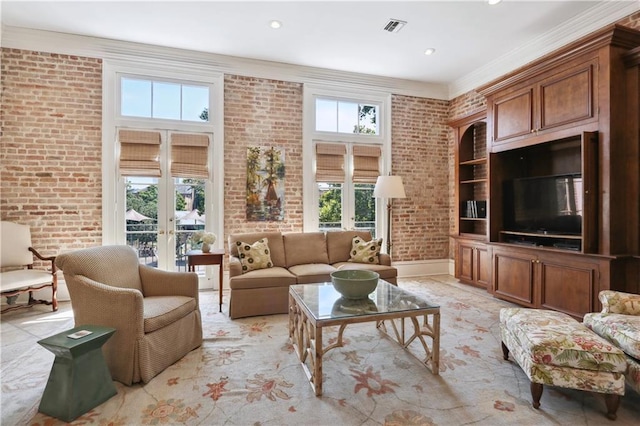 living room with brick wall, a healthy amount of sunlight, ornamental molding, and french doors