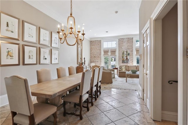dining room with a chandelier, stone tile flooring, baseboards, and ornamental molding