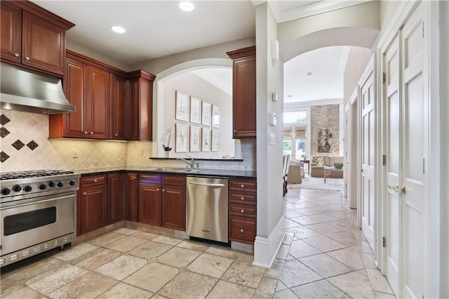 kitchen with stone tile floors, arched walkways, under cabinet range hood, appliances with stainless steel finishes, and backsplash