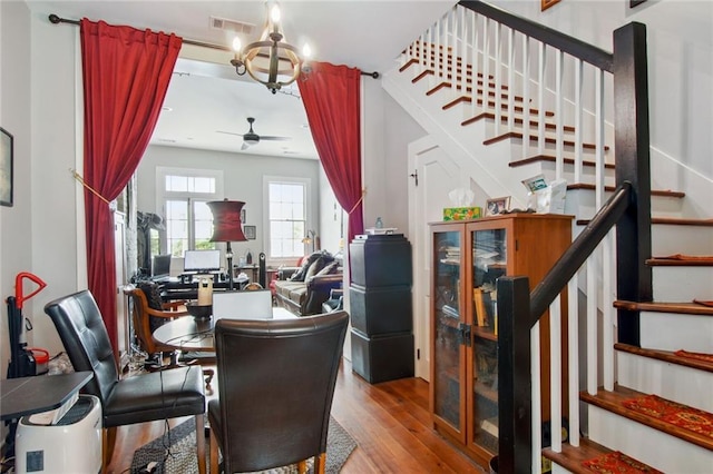 dining space with ceiling fan with notable chandelier and hardwood / wood-style floors