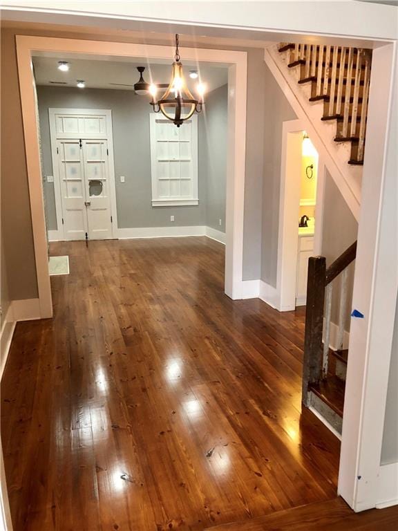 unfurnished dining area featuring dark wood-type flooring and an inviting chandelier