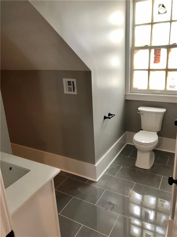 bathroom with toilet, tile patterned flooring, and vanity