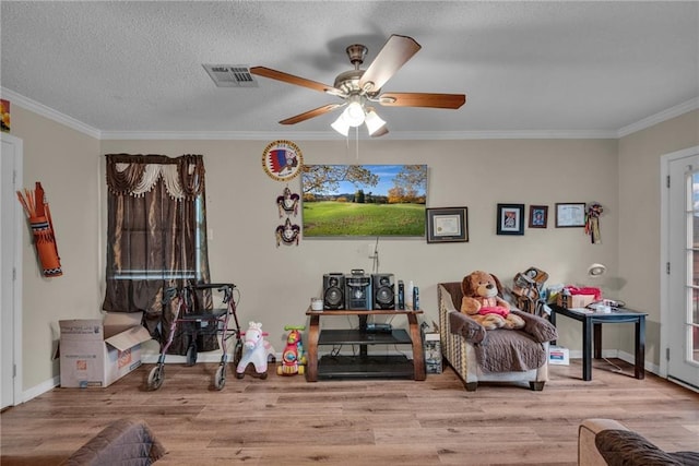 sitting room with ceiling fan, light wood-type flooring, a textured ceiling, and ornamental molding