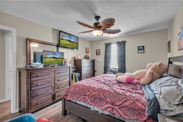 bedroom with ceiling fan, a textured ceiling, and light wood-type flooring