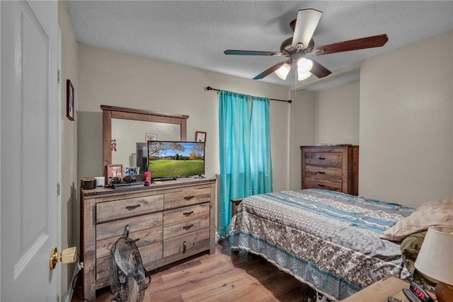 bedroom featuring ceiling fan, a textured ceiling, and light wood-type flooring