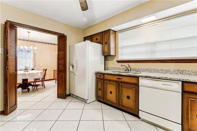 kitchen featuring decorative light fixtures, sink, an inviting chandelier, white appliances, and light stone counters