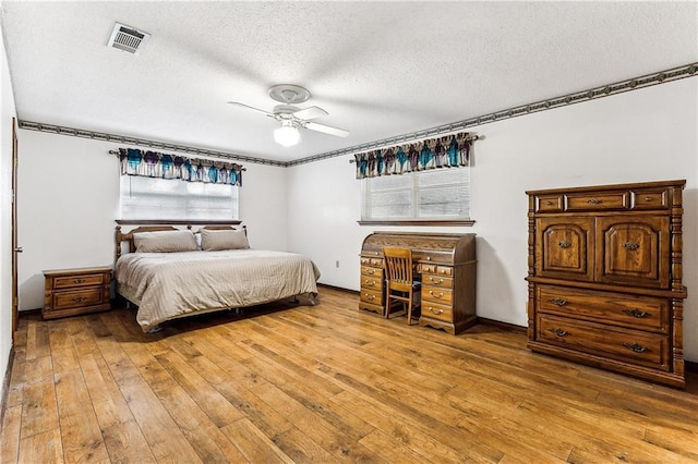 bedroom with ceiling fan, light hardwood / wood-style floors, and a textured ceiling